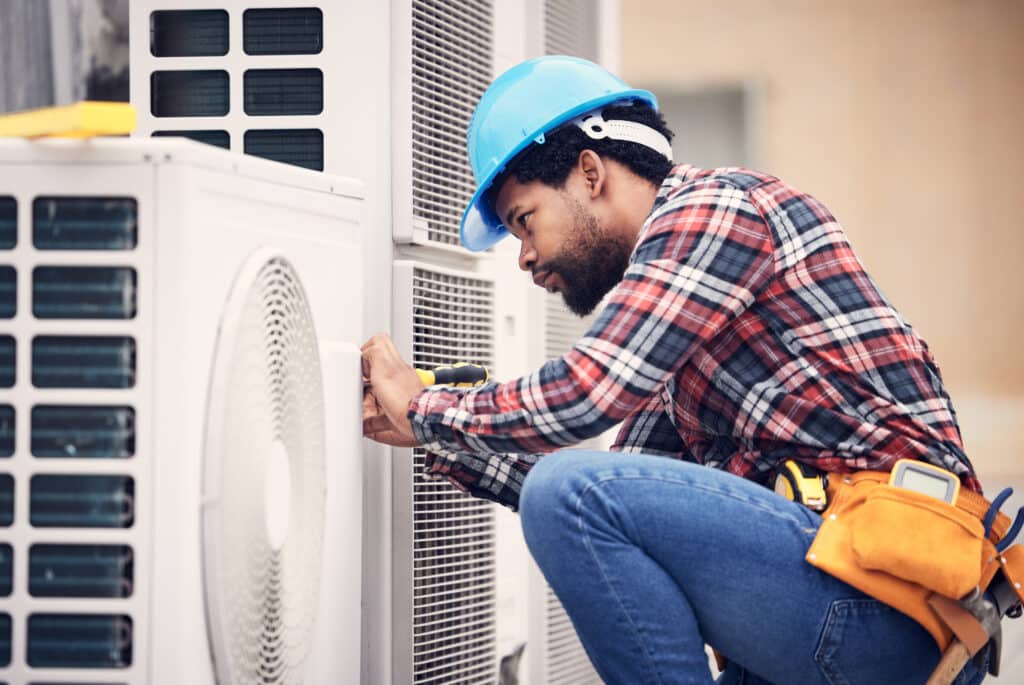 A man, electrician and maintenance on air conditioner with engineering and handyman working with tools on roof. AC repair in Sedona, professional male technician outdoor and power generator with service.