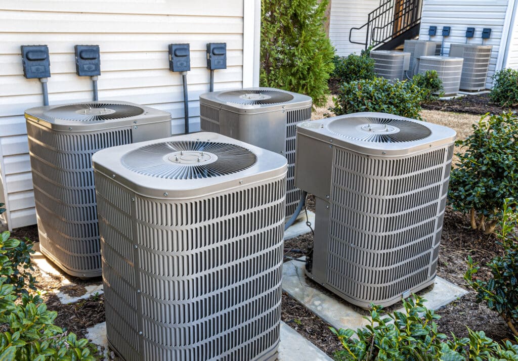 A horizontal shot of four residential HVAC systems outside.